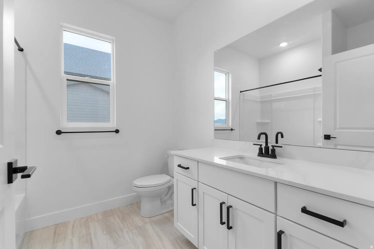 White vanity with black hardware, integrated sink, and white countertop