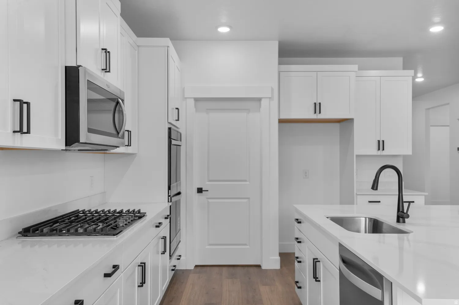 Modern kitchen featuring white cabinetry, stainless steel appliances, a gas cooktop, a built-in double oven, and wood-finish flooring