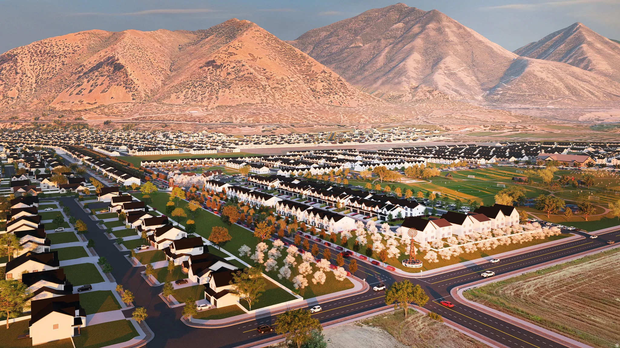 Expansive community with varied architectural styles, mountain backdrop, paved roads, and green spaces