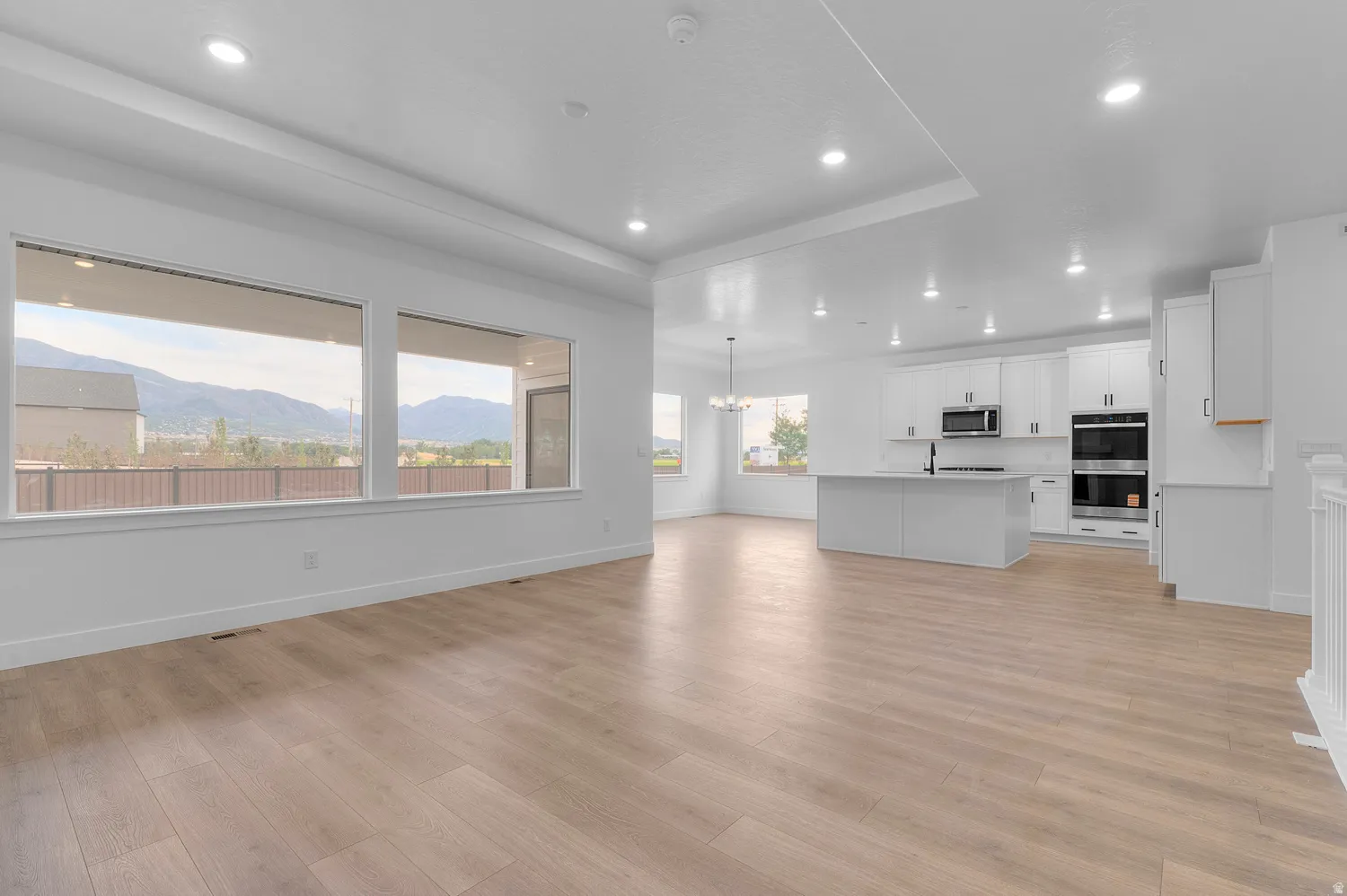 Open-concept living area with wood-finish flooring, white walls, and recessed lighting