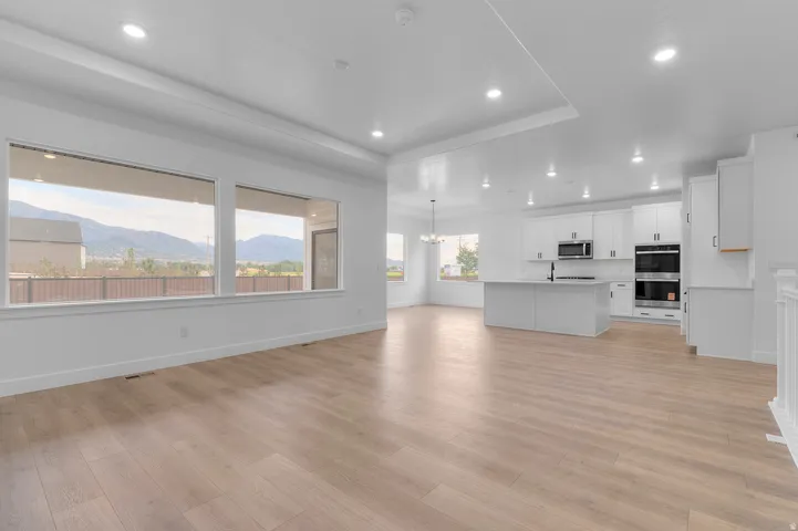 Open-concept living area with wood-finish flooring, white walls, and recessed lighting