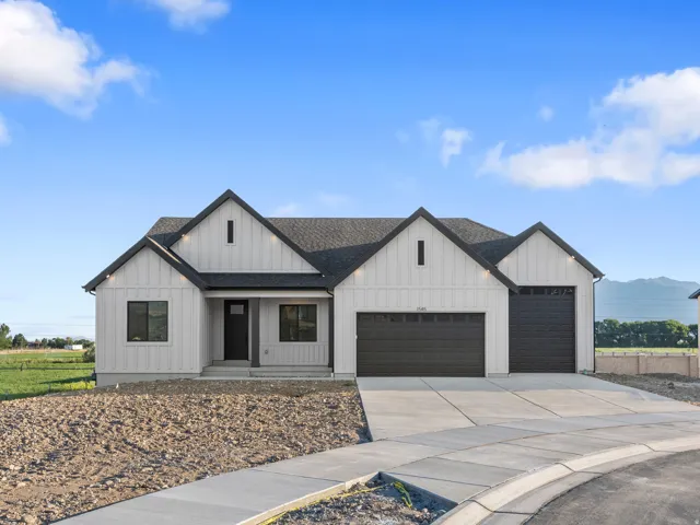 Contemporary exterior featuring vertical white siding, dark trim accents, a dark asphalt shingle roof, and an attached two-car garage with dark paneled doors