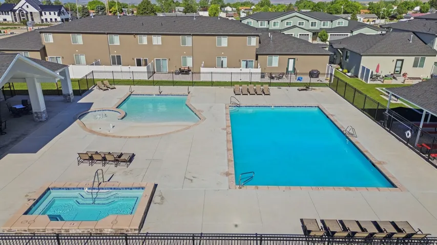 Expansive outdoor amenity area featuring a large rectangular pool, a second free-form pool with a shallow entry, and an integrated spa