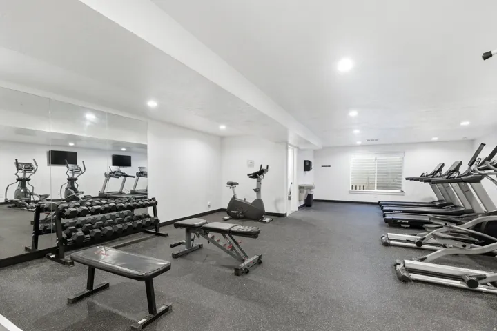Fitness room featuring wall-mounted mirrors, recessed lighting, and rubberized flooring