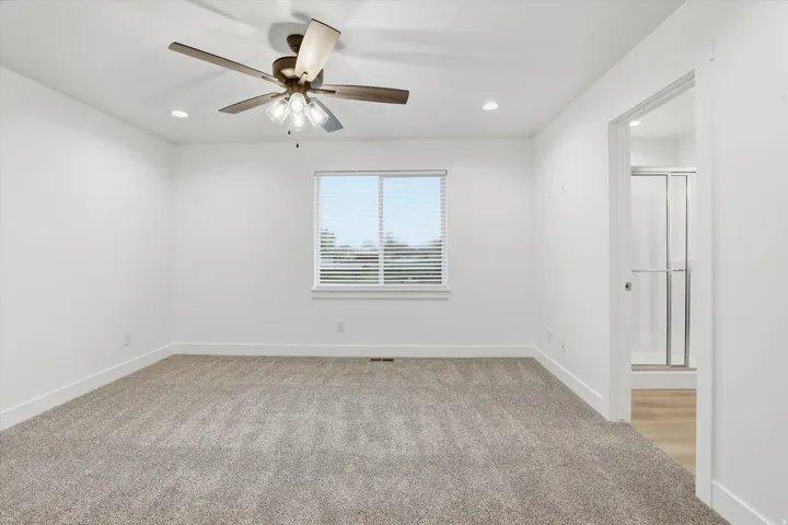 Spacious room featuring carpet flooring, a ceiling fan with integrated lighting, recessed lighting, and a window with blinds
