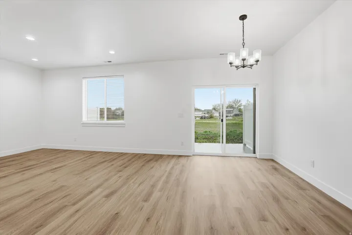 Wood-finish flooring, recessed lighting, contemporary chandelier, sliding glass door, and backyard access