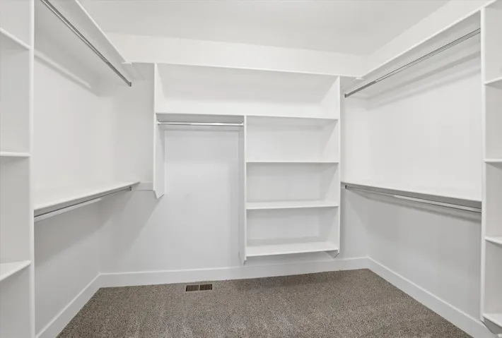 White built-in shelving, multiple hanging rods, and carpet flooring