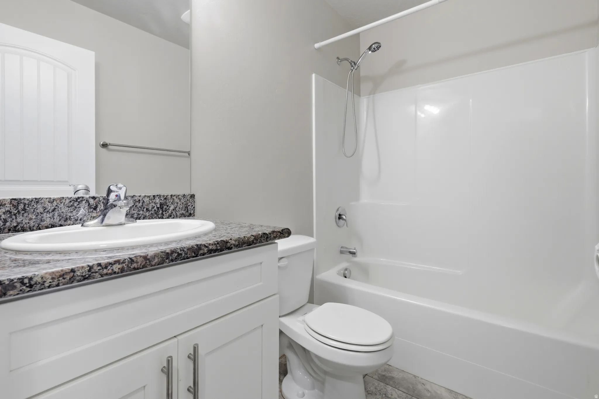 White vanity with a stone-finish countertop and undermount sink