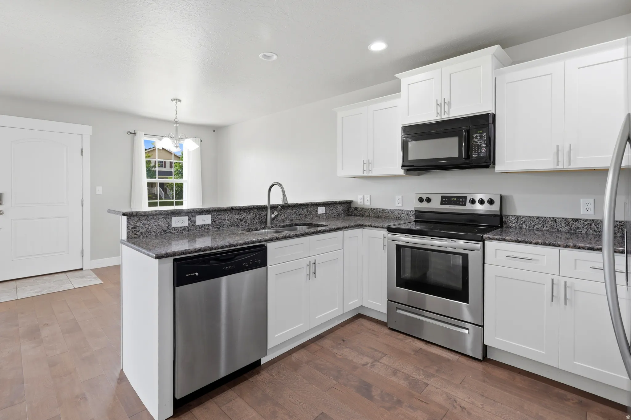 Kitchen featuring white cabinetry, dark stone-finish countertops, and stainless steel appliances