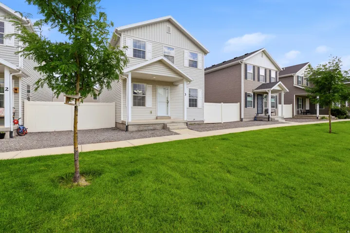 Cream-colored siding exterior with white window shutters, covered front porch, and a gravel front yard