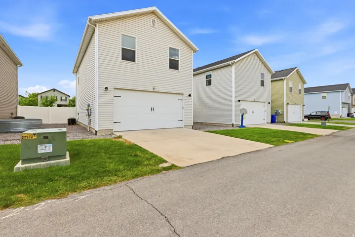 Two-story residence featuring light-colored siding, a white garage door, and a concrete driveway