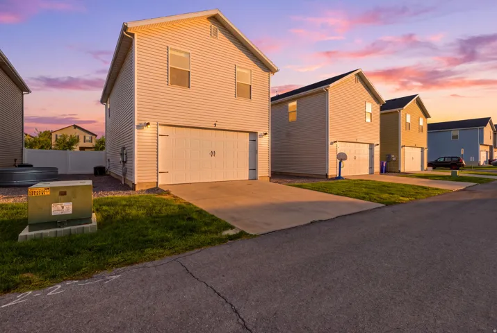 White vinyl siding exterior with a pitched roof, attached garage, and concrete driveway