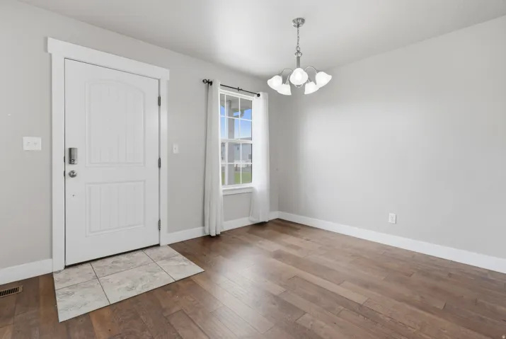 Entry area with wood-finish flooring, a white paneled door, and a multi-light chandelier