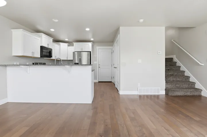 Kitchen featuring white cabinetry, stainless steel appliances, and a breakfast bar with stone-finish countertop