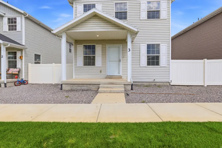 Two-story vinyl siding exterior with a covered porch, white window shutters, concrete porch steps, and gravel landscaping