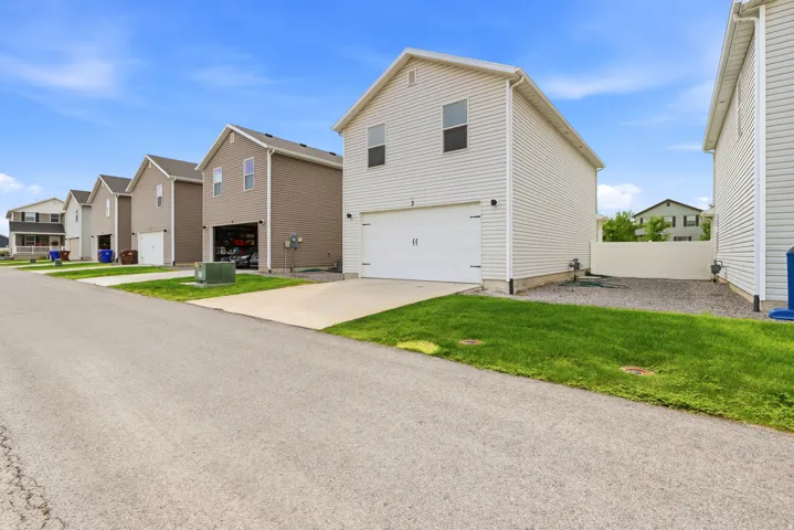 Two-story residence featuring light-colored siding, a two-car garage, and a manicured lawn