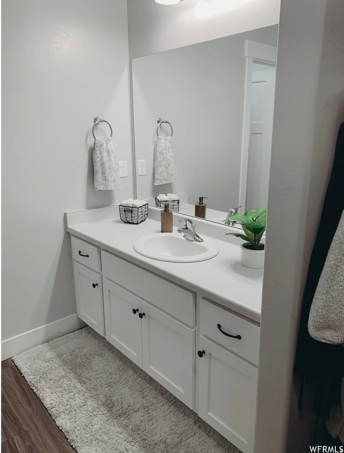 White vanity with integrated sink, chrome faucet, and expansive wall-mounted mirror