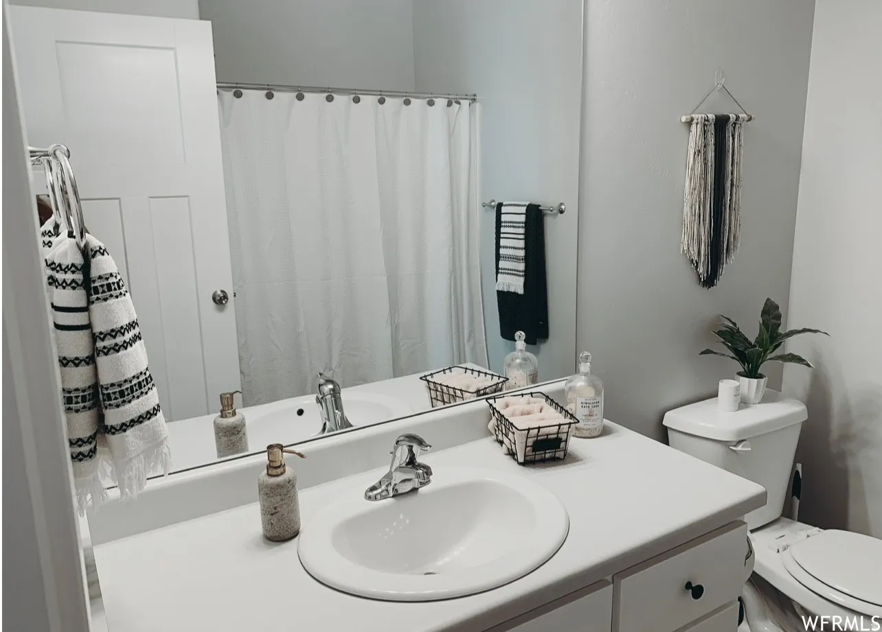 Single vanity with a white countertop and integrated sink, chrome faucet, and a wall-mounted mirror