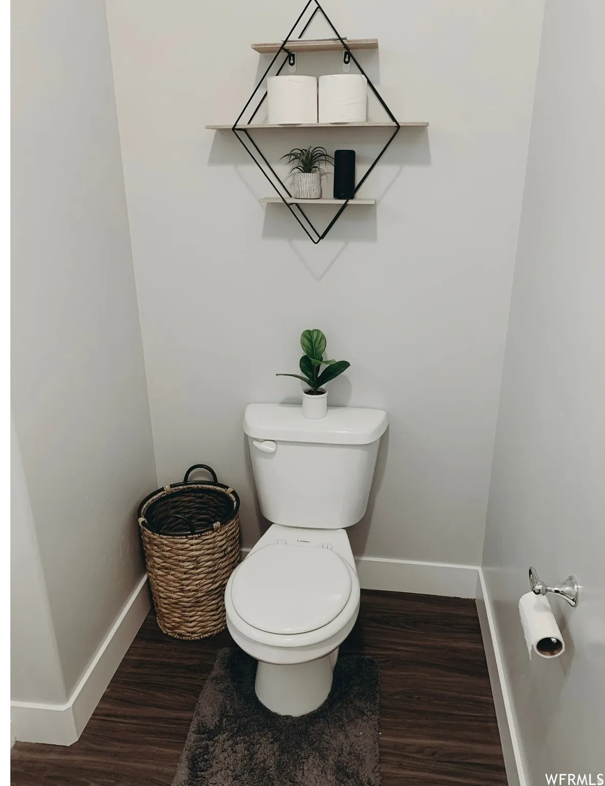White toilet with a built-in toilet paper holder and decorative wall shelving