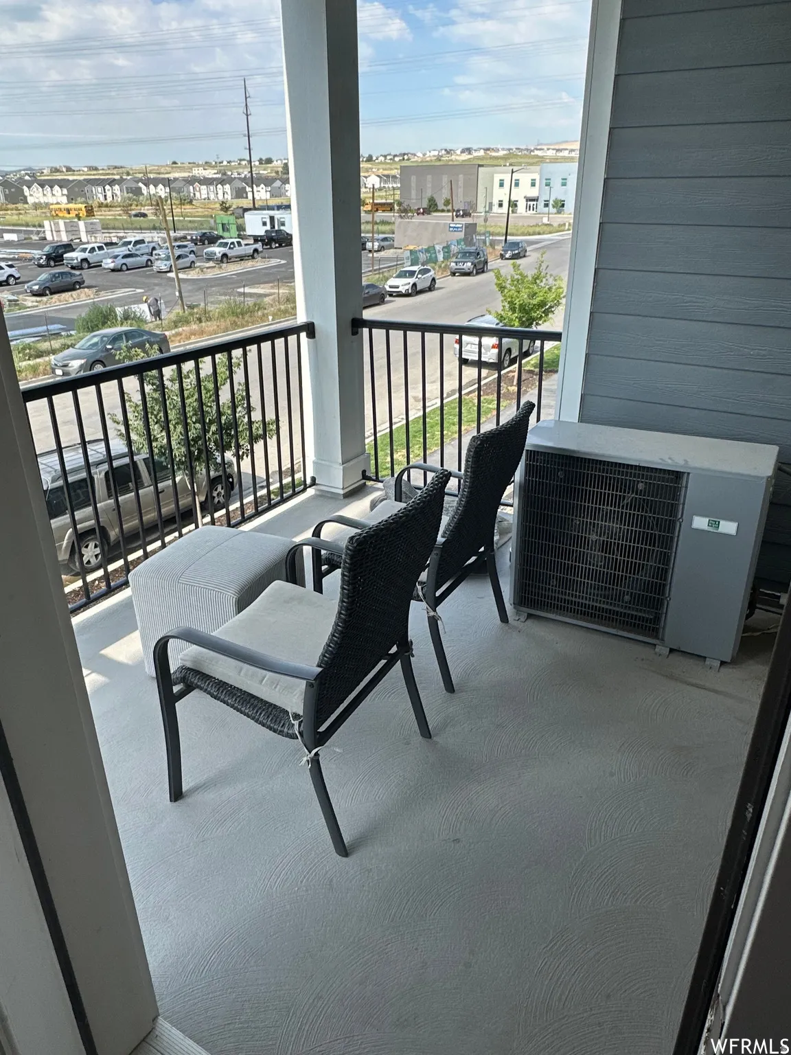 Balcony featuring a smooth concrete surface, white columns, and black metal railings