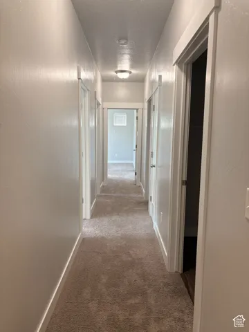 Hallway with plush carpeting, white walls, and recessed lighting