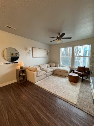Wood-finish flooring, ceiling fan with integrated lighting, recessed lighting, and large windows providing natural illumination