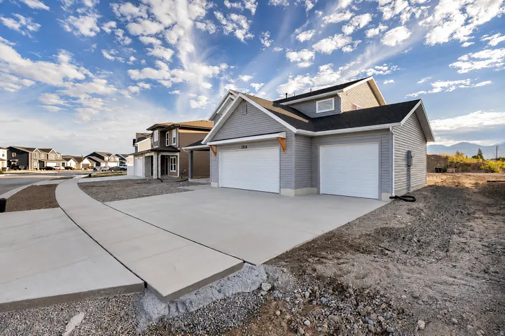 Exterior featuring light gray siding, a two-car garage, a concrete driveway, and a concrete walkway