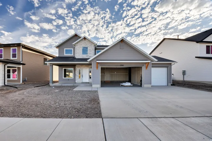 Two-story residence featuring light gray siding with stone accents, a two-car garage, and a single-car garage