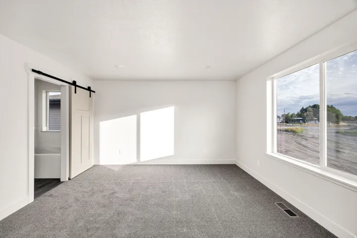 Wall-to-wall carpeting, recessed ceiling lighting, and a sliding barn door