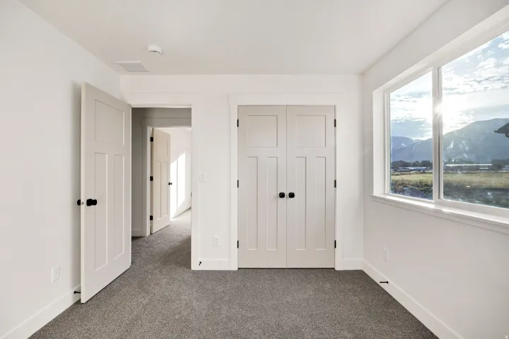 Window with mountain scenery, white interior paint, white doors with black hardware, carpeted flooring, and baseboard trim