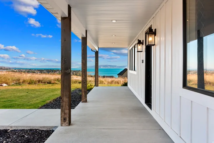 Covered porch with exposed wood columns, concrete flooring, and recessed ceiling lighting