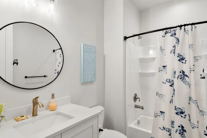 Bathroom featuring a white vanity with an integrated sink, bronze-finish faucet, and a circular black-framed mirror