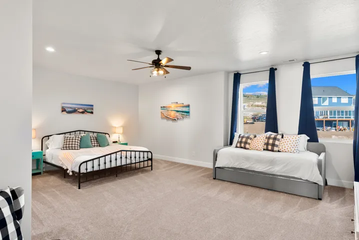 Carpeted room featuring a ceiling fan, recessed lighting, and multiple windows