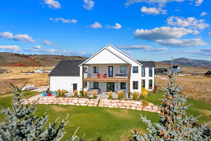 Modern farmhouse exterior with white siding, black-framed windows, and an upper-level balcony