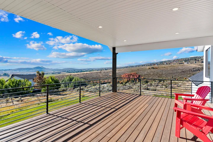 Covered outdoor deck with wood-finish flooring, recessed lighting, and a cable railing system