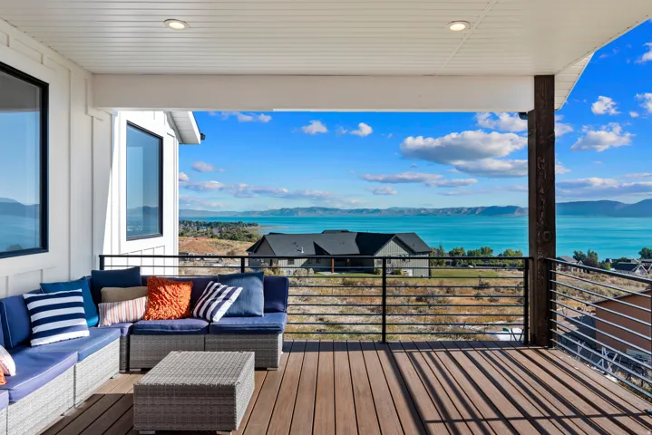 Covered outdoor deck with wood-finish flooring, recessed lighting, and a black horizontal bar railing