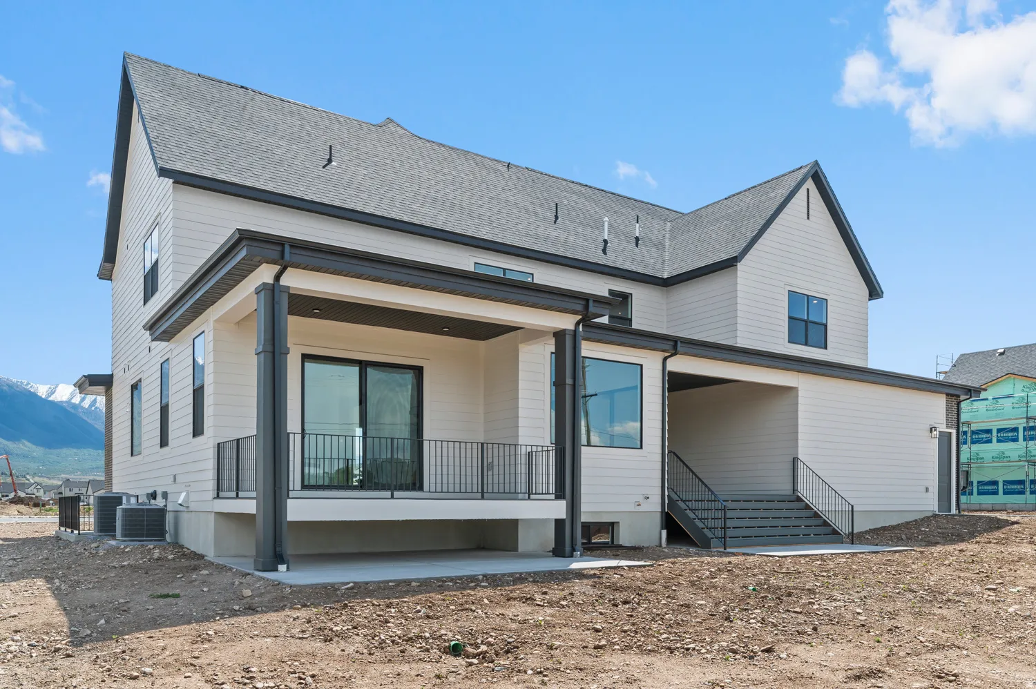 Contemporary exterior with light-toned siding, dark trim, and a covered balcony featuring dark railings