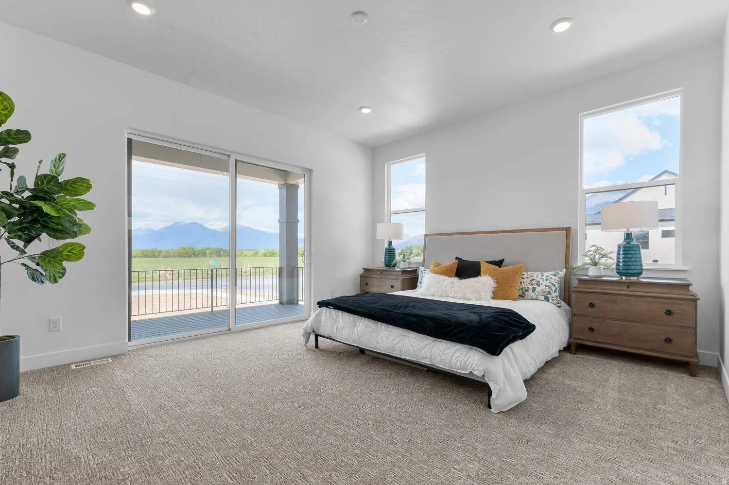 Sliding glass door opening onto a private balcony with metal railing, recessed lighting, and two large windows