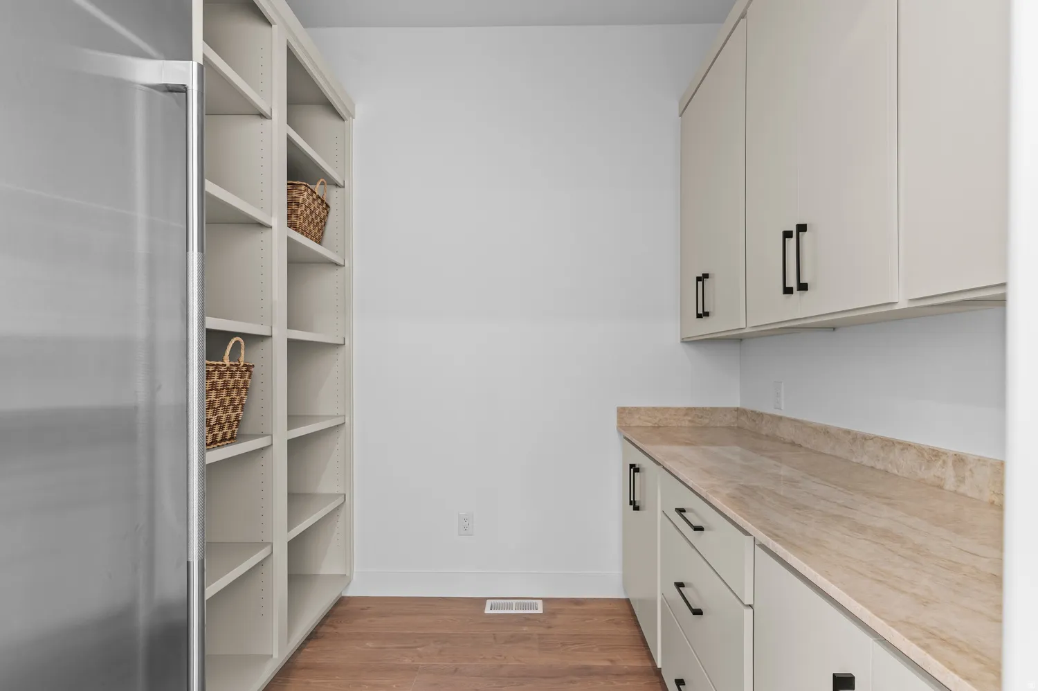 Built-in shelving, wood-finish flooring, upper and lower cabinetry, stone countertop, stainless steel appliance