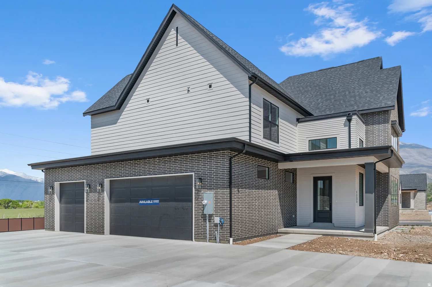 Contemporary home exterior featuring a multi-tone brick and horizontal siding facade, dark-frame windows, a prominent gable roofline, and an attached two-car garage