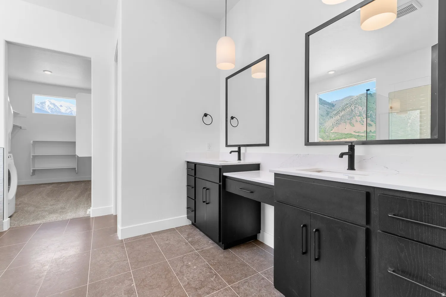 White countertop vanities with black finish cabinetry, rectangular mirrors, and pendant lighting