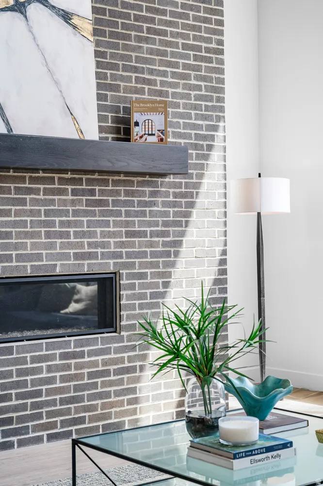 Brick fireplace surround with a linear firebox, a floating wood mantel, and light wood-finish flooring