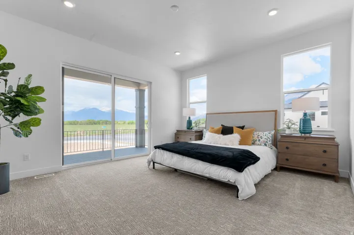 Sliding glass door opening onto a private balcony with metal railing, recessed lighting, and two large windows