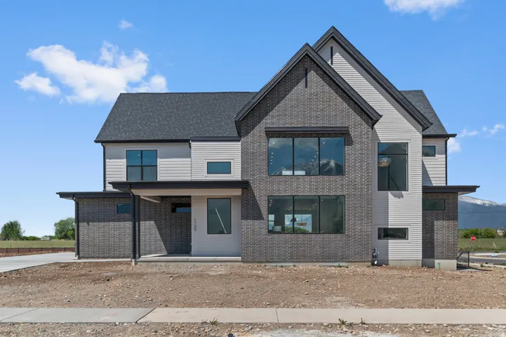 Modern exterior featuring a prominent gabled roof, dark gray brick-style siding, light gray horizontal siding, and multiple large windows