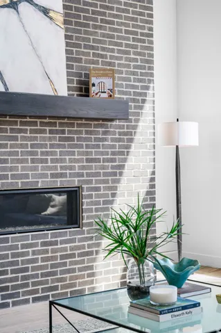 Brick fireplace surround with a linear firebox, a floating wood mantel, and light wood-finish flooring