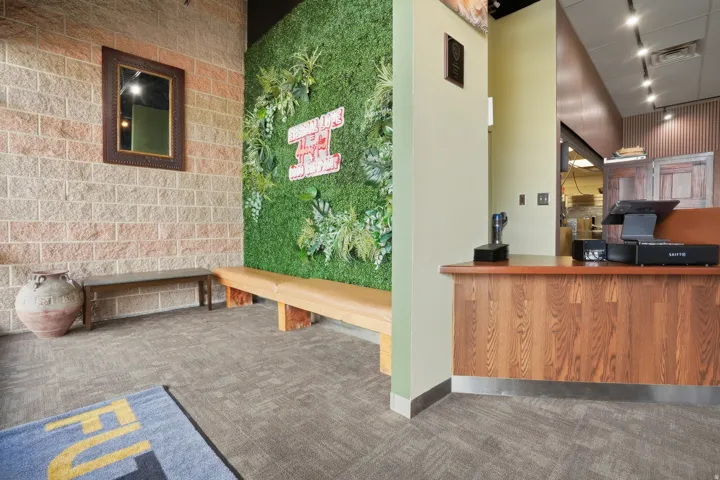 Woven carpet flooring, wood-finish reception desk, track lighting, and a green wall feature