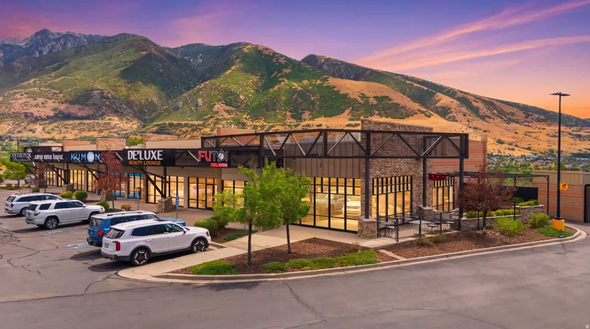 Modern commercial storefronts with expansive glass windows, stone accent facade, and mountain backdrop
