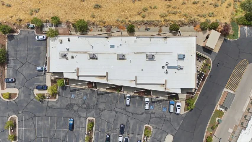 Expansive paved parking area, commercial building with a flat roof, surrounding natural landscape, and accessible paved entranceways