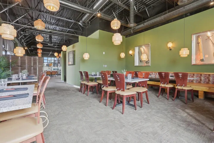 Spacious interior with exposed ceiling ductwork, decorative pendant lighting, and wall-mounted sconces
