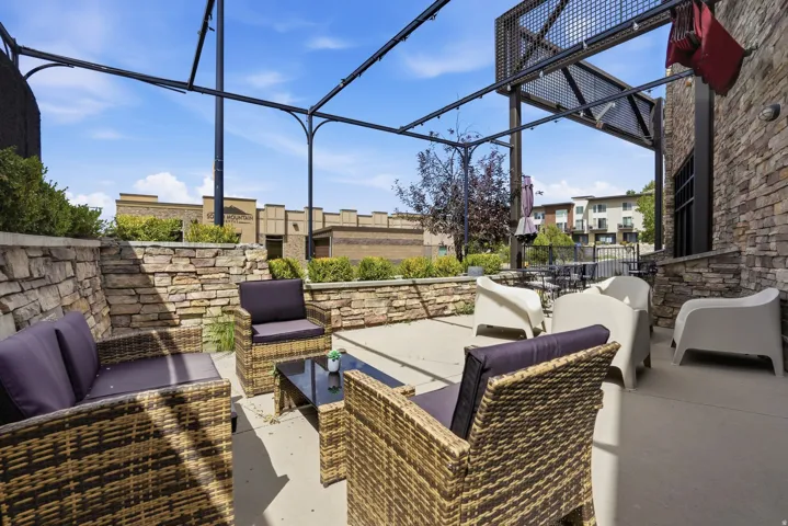 Stone veneer exterior with an integrated patio structure, featuring a concrete patio surface and raised stone planters